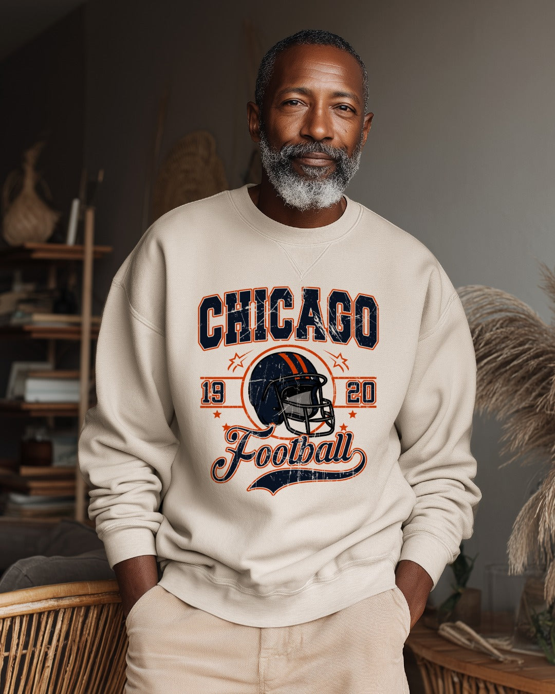 Man wearing a beige sweatshirt with 'Chicago Football' design in a room.